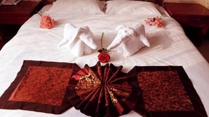 A neatly made bed with towels arranged in a heart shape, a rose, and decorative red and brown fabric pieces. - Yaxuan Hotel (Pingli)