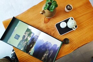A wooden table with a book, a teapot, a cup, and a small potted plant. - Tianshe Hostel (Zhangjiajie)