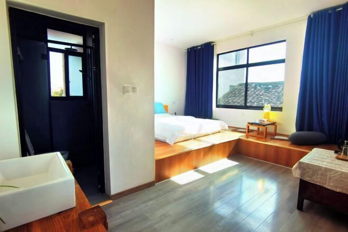 A hotel room with a bed, a window, a desk, and a bathtub.