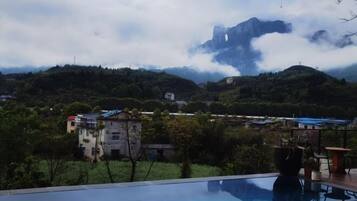 Una piscina con vistas a montañas y un pueblo al fondo.