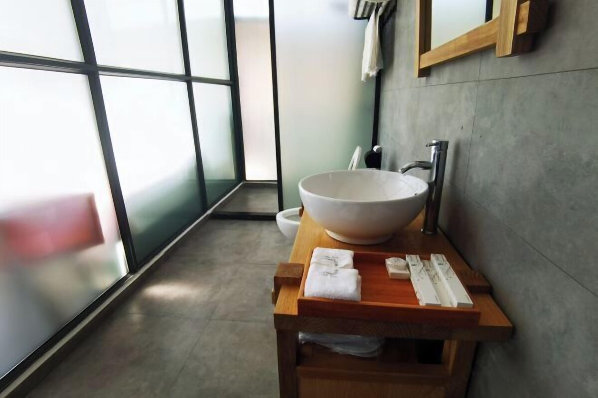 A modern bathroom with a large white vessel sink, a wooden vanity, and a mirror above it.
