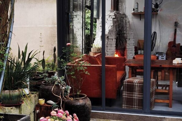 A cozy indoor space with a stone fireplace, a dining table, and various potted plants. - Tianshe Hostel (Zhangjiajie)