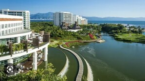 Ein modernes Hotel mit gewundener Wasserstraße, üppiger Bepflanzung und Meerblick.
