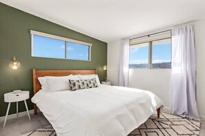 Una camera da letto con un letto grande, un comodino, una finestra con tende e vista sull'esterno.