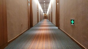 Un largo y estrecho pasillo de hotel con piso alfombrado y paredes de madera.