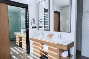 Un baño moderno con dos lavamanos, espejos y zona de ducha.