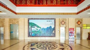 Un vestíbulo con un gran mural, ascensores y una barandilla decorativa tradicional en rojo y dorado.