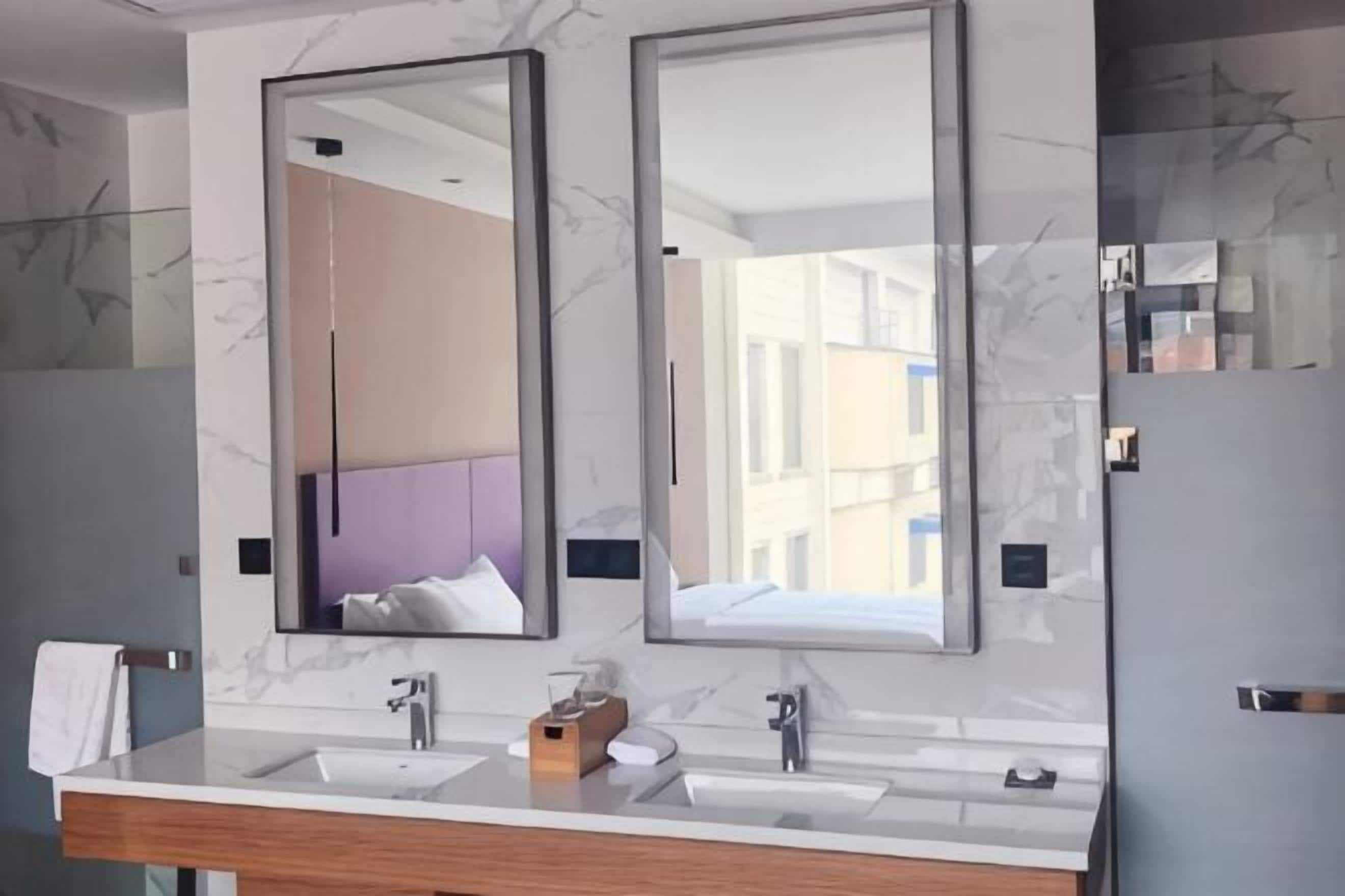 Ein Badezimmer mit zwei Spiegeln, einem Holzwaschtisch und einer Marmorwand.