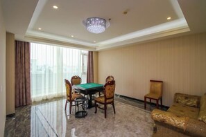Una habitación con mesa de billar, cuatro sillas, sofá y candelabro.