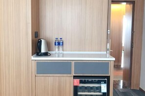 Une petite cuisine équipée d’une machine à café, de bouteilles d’eau et d’un four à micro-ondes.