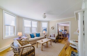 Un salon spacieux comprenant un canapé, des fauteuils, une table basse et un coin repas avec une table et des chaises.