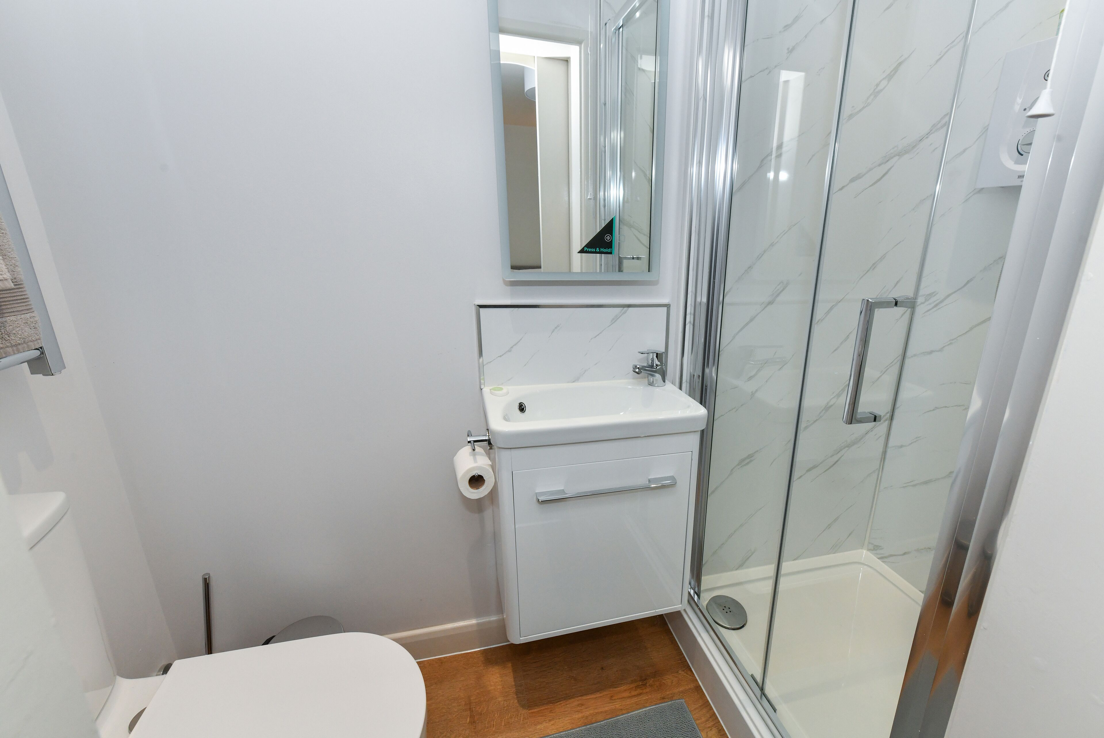A bathroom with a toilet, sink, and glass shower enclosure.