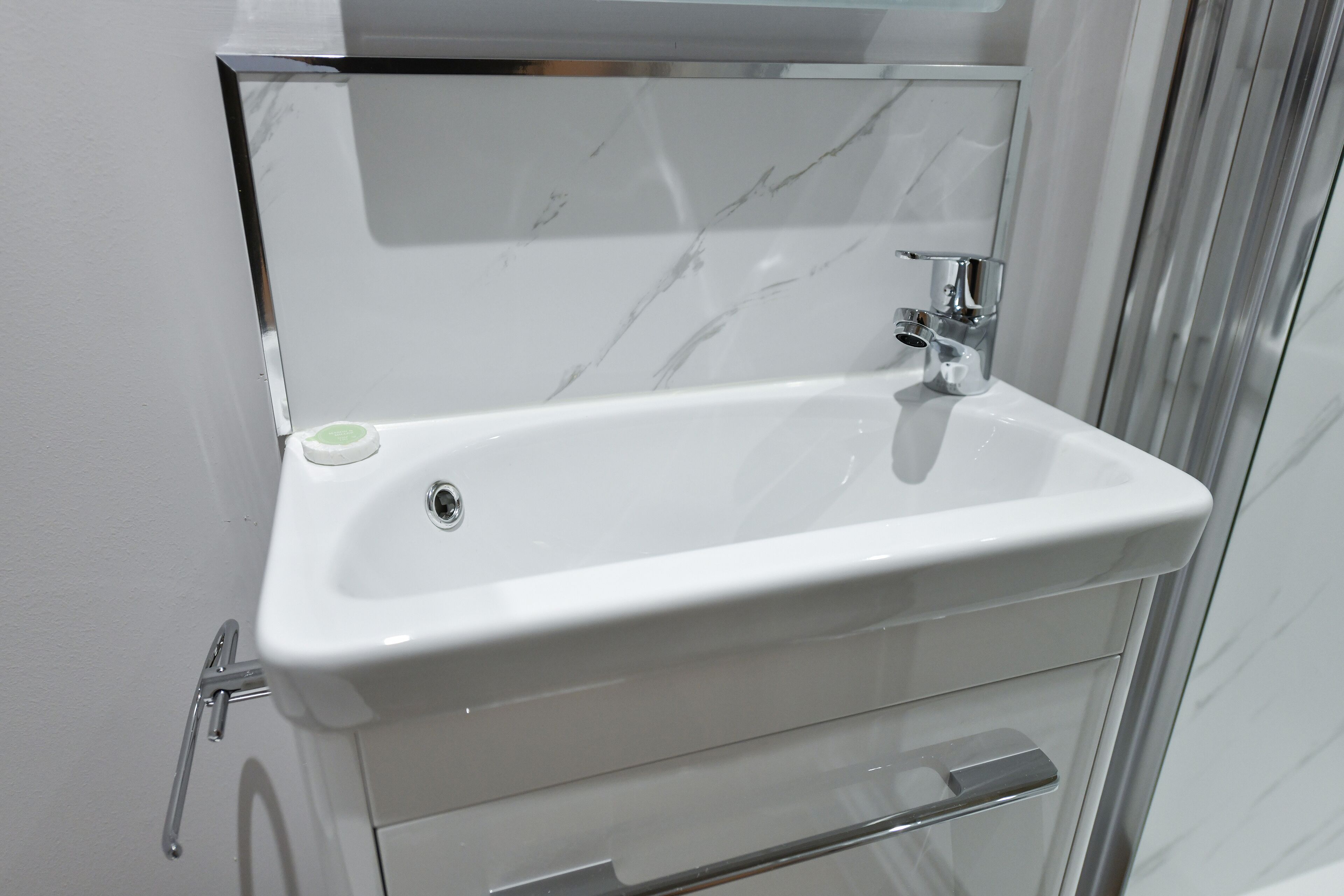 A bathroom with a white sink, chrome faucet, and a glass shower enclosure.