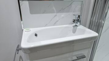 A bathroom with a white sink, chrome faucet, and a glass shower enclosure.