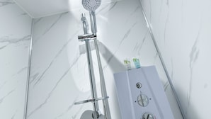 Un baño moderno con ducha, pared de mármol blanco y un pedestal blanco con panel de control.