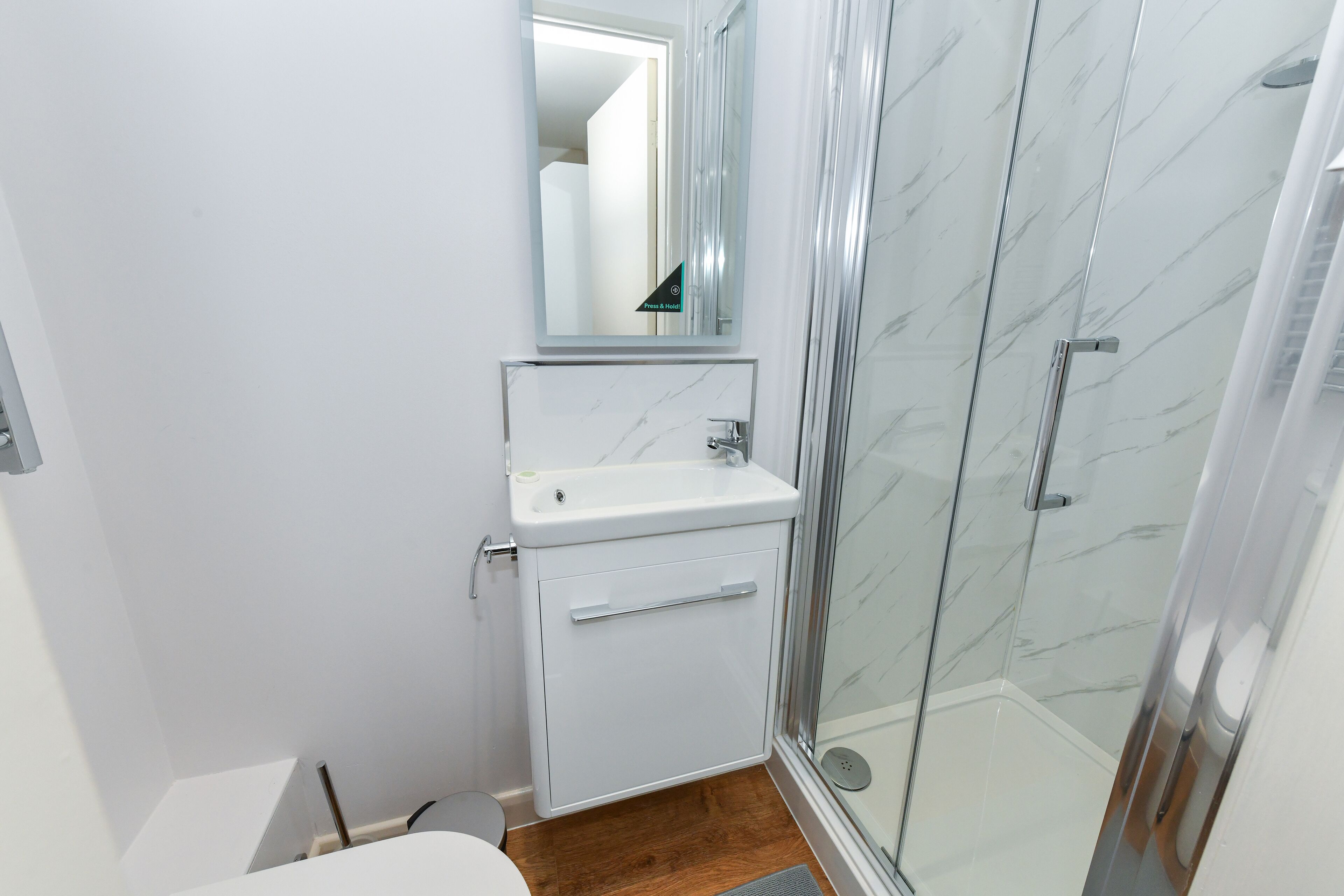 A bathroom with a glass shower enclosure, a white sink, and a mirror above the sink.