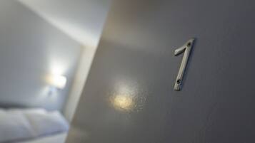 A close-up of a metallic number '1' on a grey wall, likely indicating a room number in a hotel.