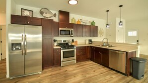 Una cocina moderna con electrodomésticos de acero inoxidable, armarios de madera y suelo de madera.