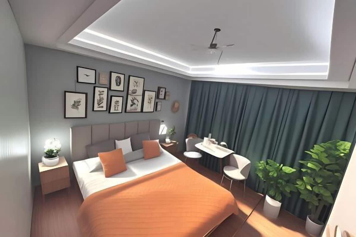 Una habitación de hotel moderna con cama, mesitas de noche, escritorio, sillas, ventilador de techo y un cuadro en la pared.