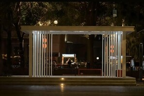 Un espace extérieur abrité, doté de barrières verticales et d’un banc.