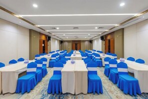 Un salón de conferencias con filas de mesas y sillas, equipado con tarjetas de identificación y botellas de agua.