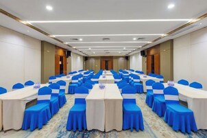 Un salón de conferencias con filas de mesas y sillas, equipado con tarjetas de identificación y botellas de agua.