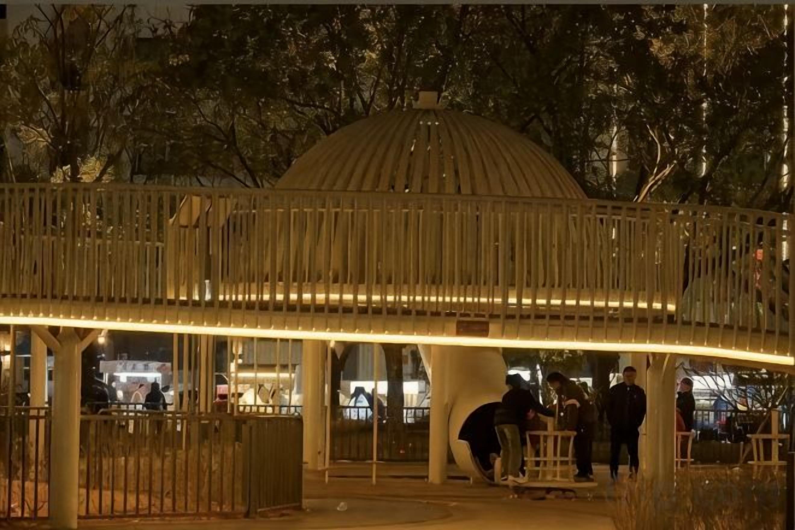 Un pasillo cubierto con estructura en forma de cúpula, barandillas y una entrada con portón.