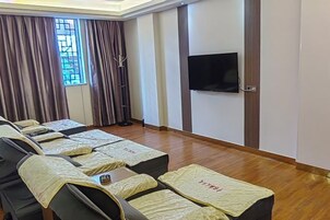 Una habitación con camillas de masaje, un televisor y una ventana con cortinas.