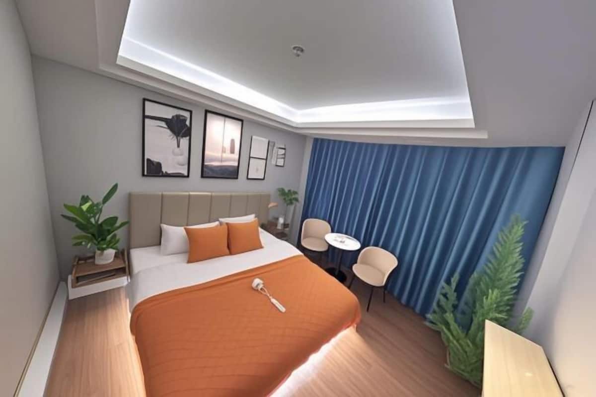 Una habitación de hotel moderna con cama, escritorio, sillas y una mesita.