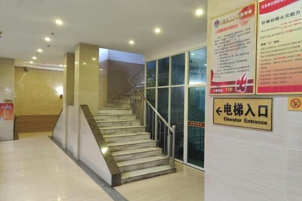 A staircase with a handrail leading to an elevator entrance.