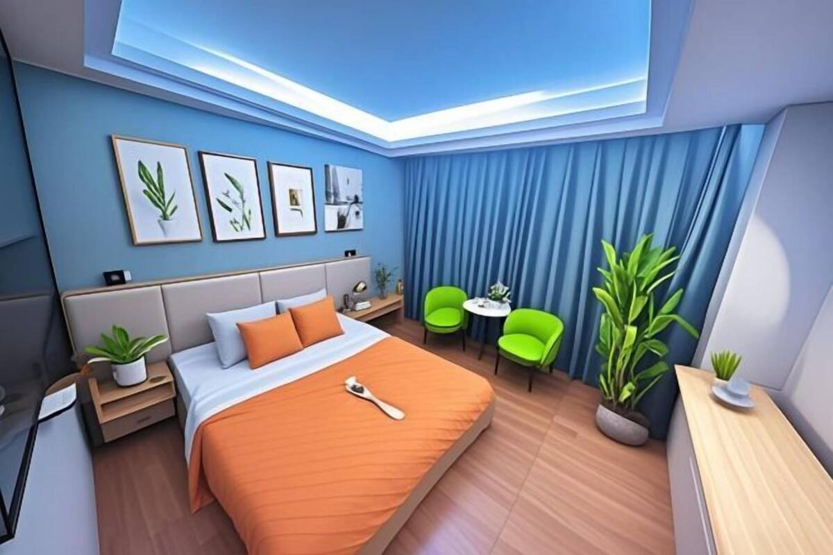 Una habitación de hotel moderna con cama, mesitas de noche, escritorio, sillas y un tragaluz.