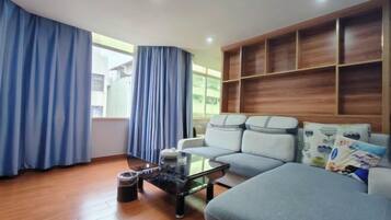 Una sala moderna con un sofá, una mesa de centro de vidrio y una estantería de madera.