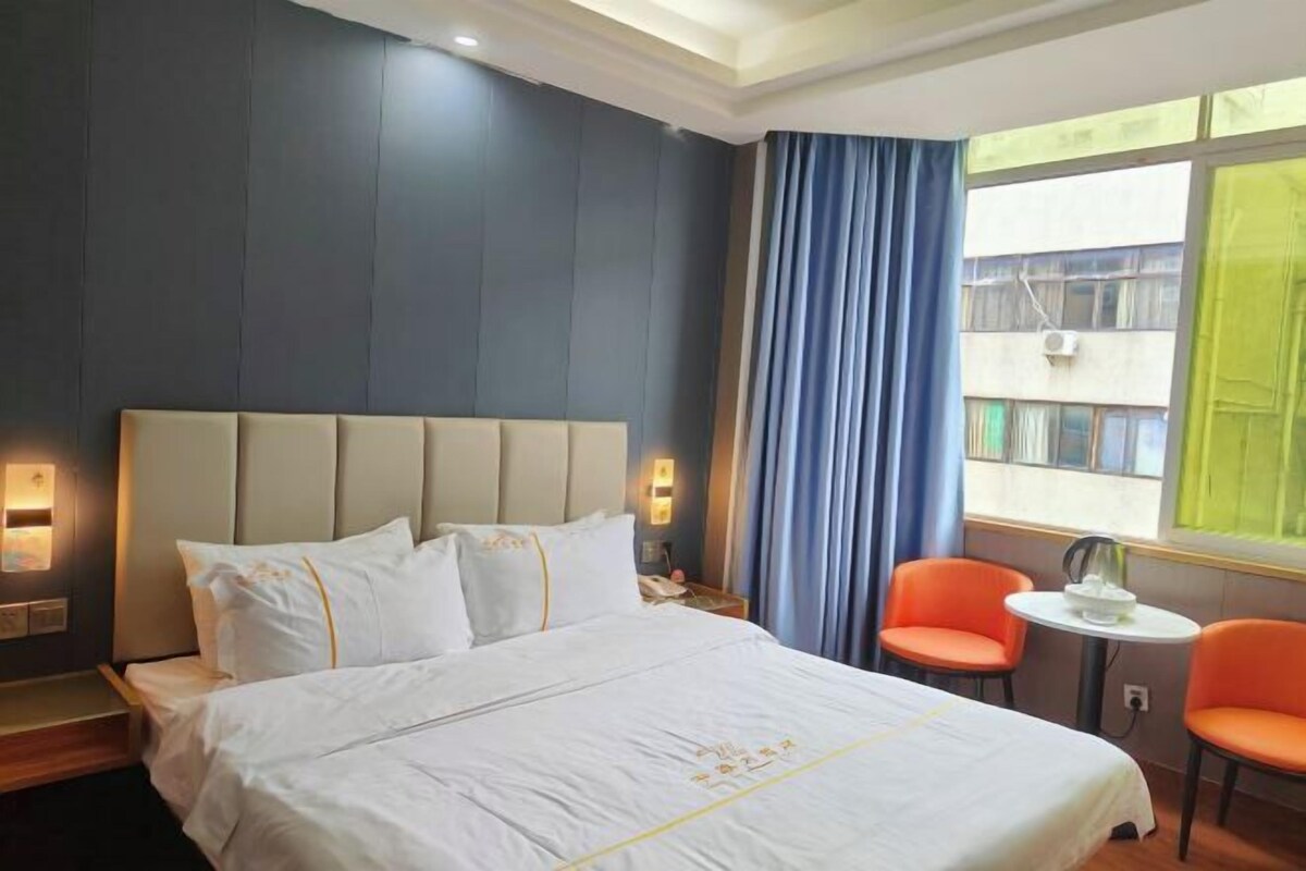 A hotel room with a large bed, two bedside tables, a small table, and two chairs.