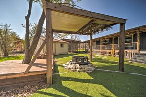 A covered outdoor area with a wooden pergola, a stone fire pit, and a fenced patio. - 'The Barn' Fredericksburg Wine Country Retreat (Fredericksburg)