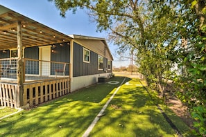 A house with a covered porch, a fenced yard, and a well-maintained lawn. - 'The Loft' Wine Country Escape in Fredericksburg! (Fredericksburg)