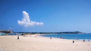 A beach with a clear sky, a sandy shore, and a few people.