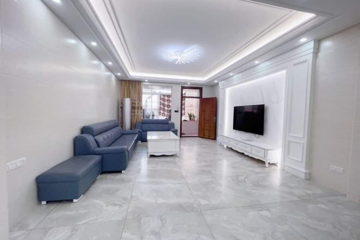 Una sala de estar moderna con un sofá modular, una mesa de centro, un televisor y un mueble blanco para televisión.