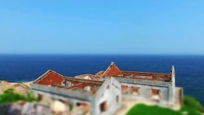 A coastal view of a historic building with multiple rooftops and a clear blue sky. - Red Bay Hesheng Homestay (Shanwei)