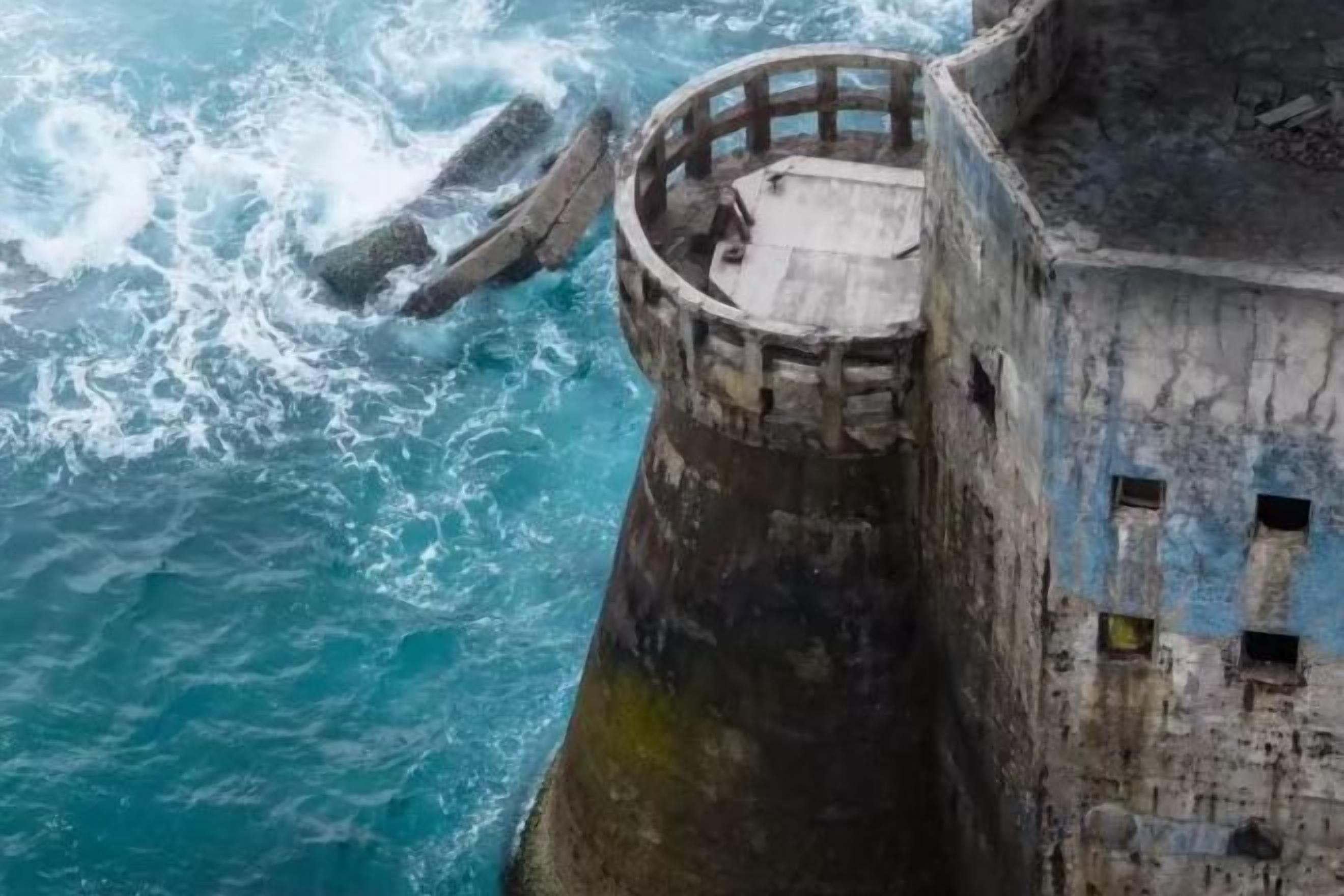 Una estructura cilíndrica de concreto con una abertura circular en la parte superior, cerca de una masa de agua.