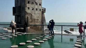 A coastal fortification with a circular arrangement of steps leading up to it, overlooking the sea.