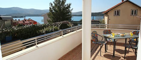 A balcony with a table and chairs, overlooking a lake and mountains.