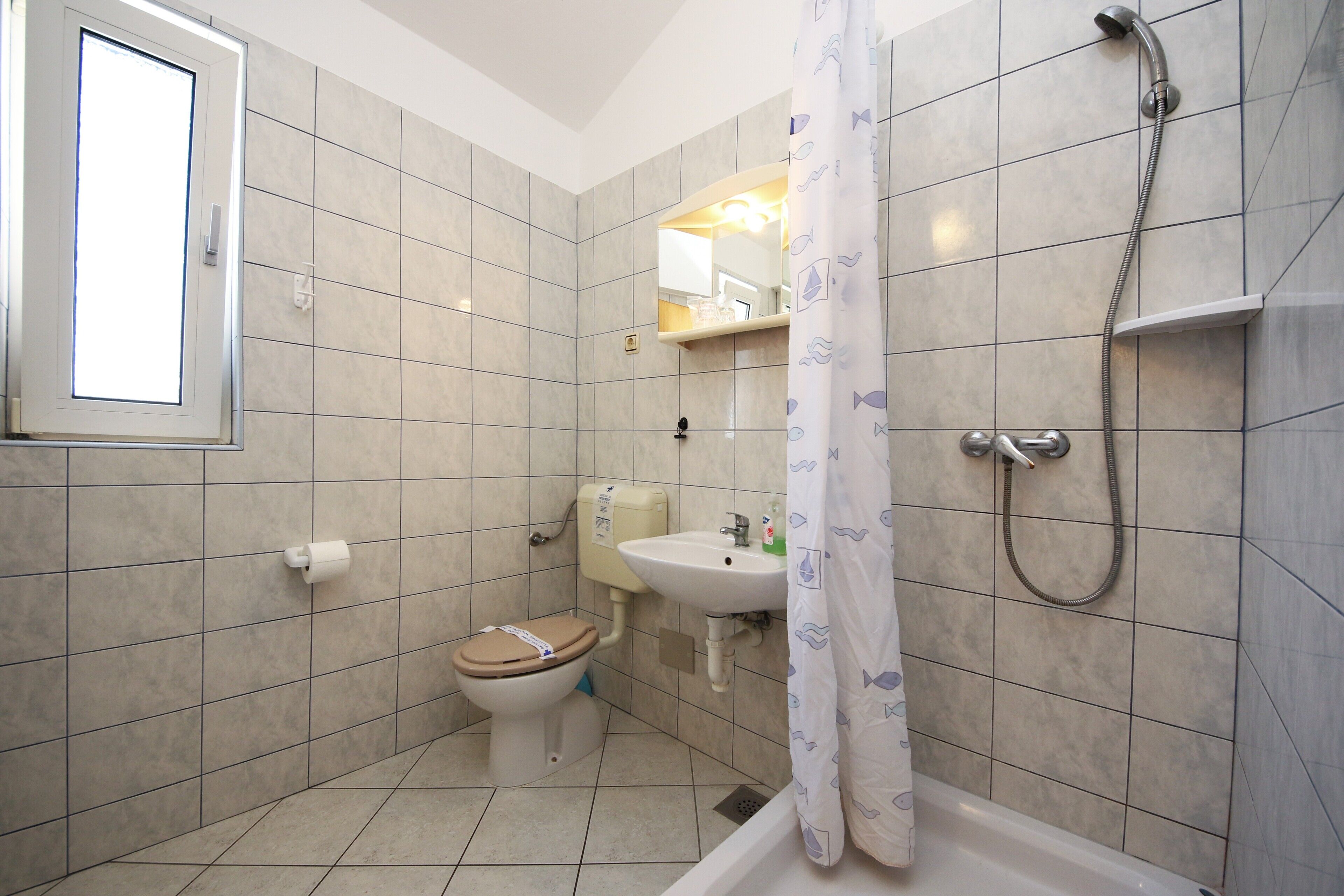 Un baño con inodoro, lavamanos, ducha y ventana.