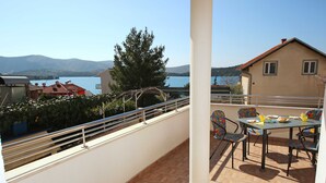 A balcony with a table and chairs, overlooking a lake and mountains. - Apartments & Rooms Villa Petra - One Bedroom Apartment with Balcony and Sea View - 2 (Žaborić)