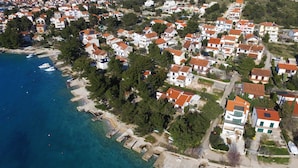 Vista aérea de una zona residencial costera con casas, un puerto deportivo y aguas azul turquesa.