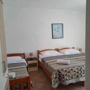 Une chambre avec deux lits, une table de chevet, une chaise et un tableau encadré au mur.