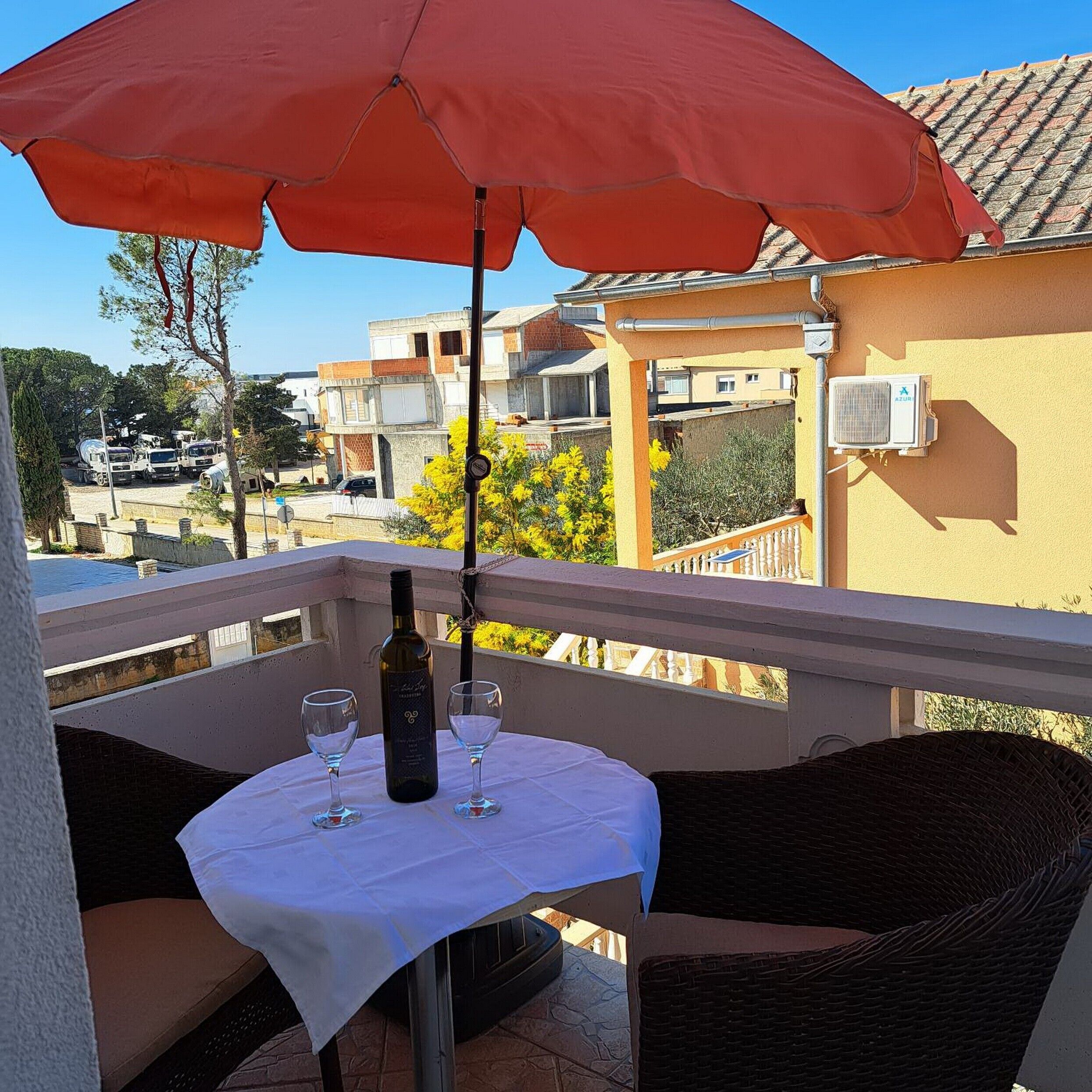A balcony with a table, two chairs, a bottle of wine, and two glasses.