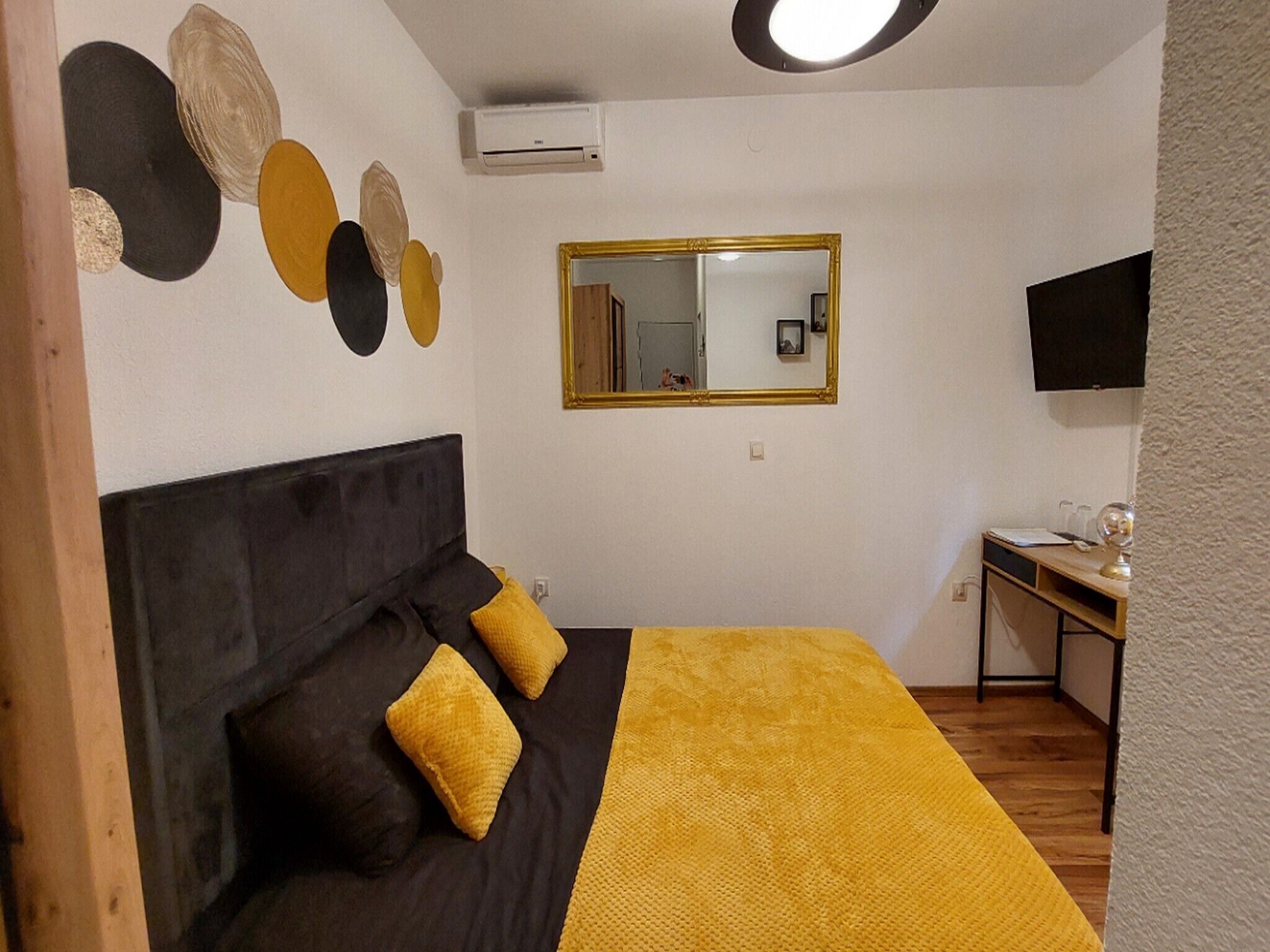 Ein Schlafzimmer mit einem Bett, einem Schreibtisch, einem Spiegel und einem Fernseher.