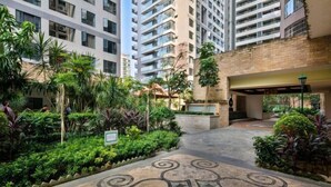 A courtyard with a patterned pathway, surrounded by lush greenery and tall buildings. - Jiuqi · Youran Seaside Holiday Apartment (Sanya)