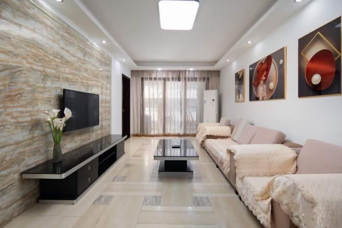 Un salon moderne avec un téléviseur à écran plat, une table basse, un canapé et un mur décoratif.