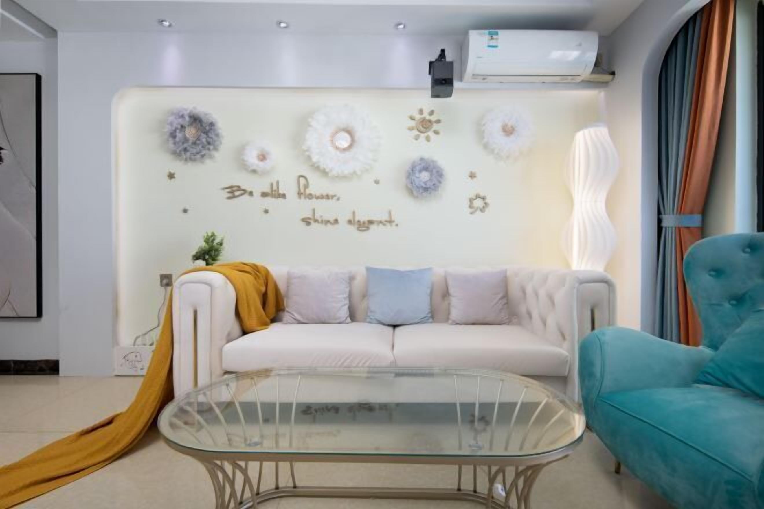 Ein modernes Wohnzimmer mit einem weißen Sofa, einem Glastisch und einem blauen Sessel.